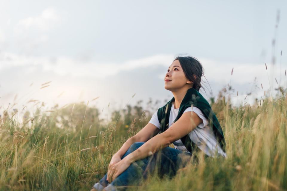 A woman sat in a field looking at the sky