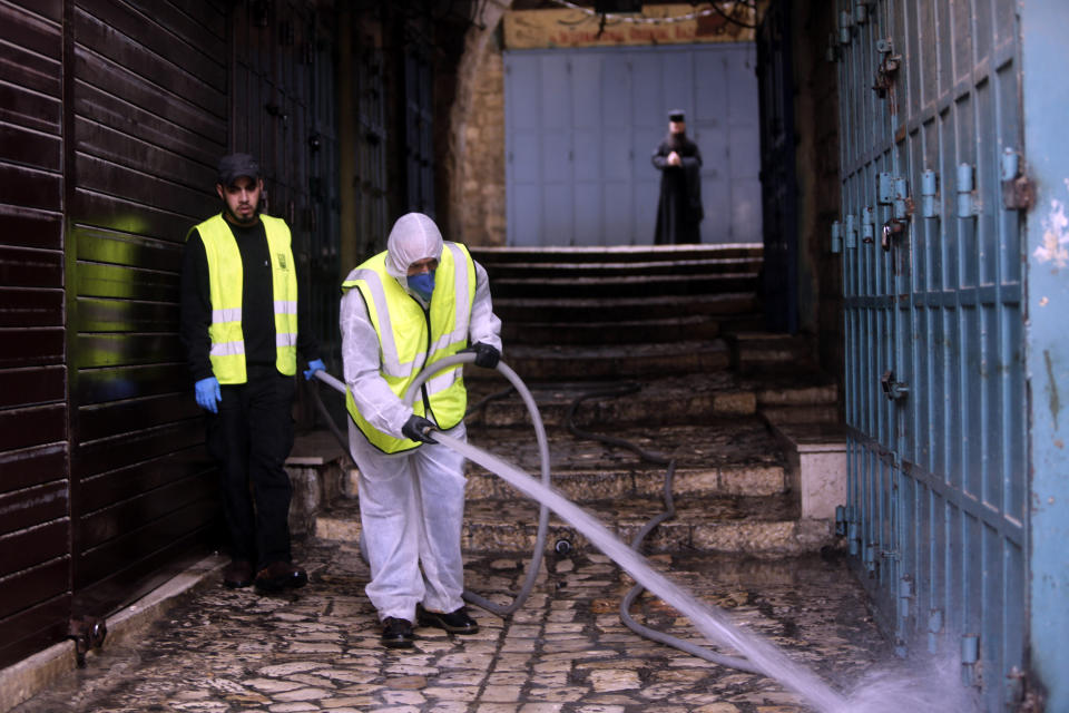 A worker disinfects an alley in Jerusalem's Old City, as general public movements are limited to prevent the spread of coronavirus, Monday, March 30, 2020. (AP Photo/Mahmoud Illean)