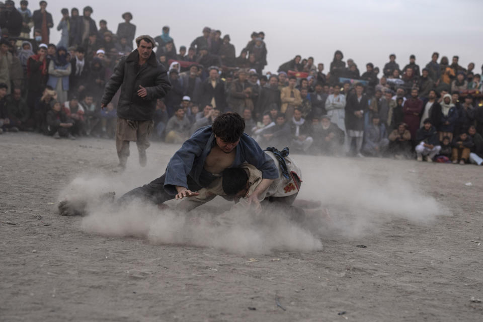 Afghan men wrestle in front of spectators in Kabul, Afghanistan, Friday, Dec. 3 , 2021. The scene is one played out each week after Friday prayers in the sprawling Chaman-e-Huzori park in downtown Kabul, where men, mainly from Afghanistan's northern provinces, gather to watch and to compete in pahlawani, a traditional form of wrestling. (AP Photo/ Petros Giannakouris)