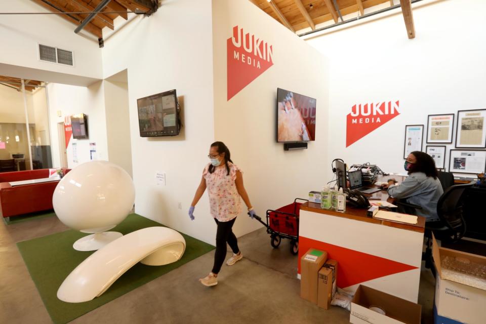 Two women in an office, one pulling a wagon.