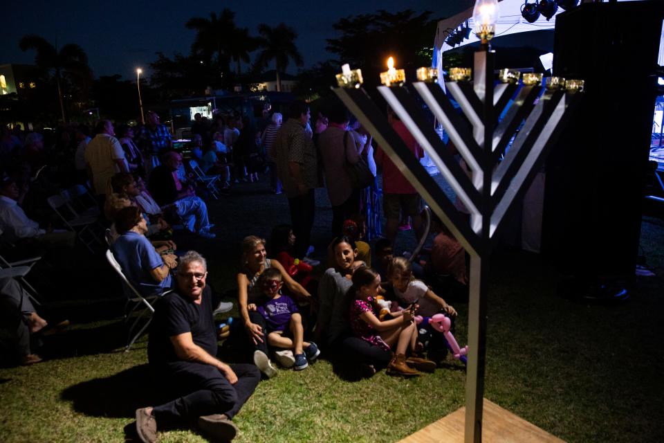 Families gather around the lit menorah listening to the Naples Klezmer Revival Band play traditional tunes during the  20th annual Hanukkah Celebration at the Mercato Lawn on Monday, Dec. 3, 2018, by the Jewish Federation.