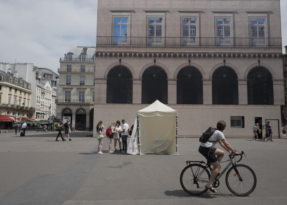 FILE - In this Friday, July 23, 2021, file photo, people line up in front of a mobile testing site in Paris, as visitors now need a special COVID pass to visit French museums or movie theaters. Europe’s famed summer holiday season is in full swing, but efforts to inoculate people against coronavirus are not taking a break. From France’s Mediterranean coast to Italy’s Adriatic beaches, health authorities are trying to make a COVID-19 shot as much a part of this summer as sunscreen and shades. (AP Photo/Rafael Yaghobzadeh, File)