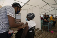 A woman receives a dose of a COVID-19 vaccine at a vaccine centre, in Soweto, Monday, Nov. 29, 2021. The World Health Organization has urged countries not to impose flight bans on southern African nations due to concerns over the new omicron variant. (AP Photo/Denis Farrell)