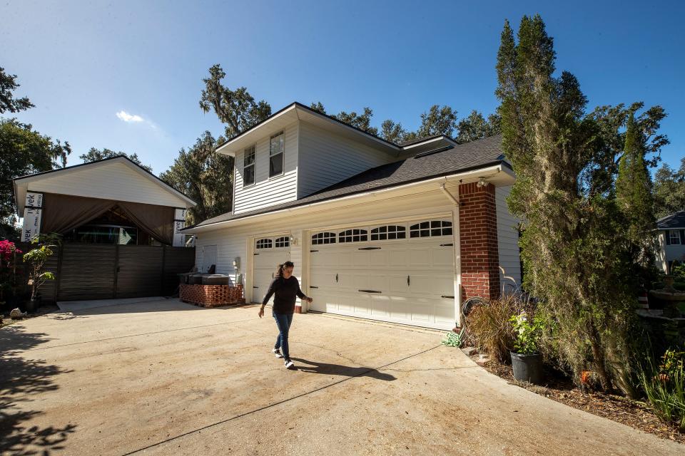 Alyne Aca walks near the carport she had construction for a motorcoach at her home in the Longwood Oaks neighborhood in South Lakeland. The neighborhood's HOA board has filed a lawsuit against Aca and her husband, saying they violated regulations by building the structure.