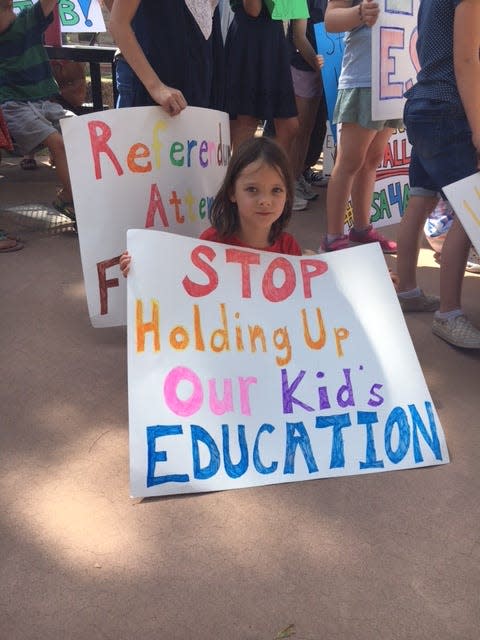 A child holds a sign on Sept. 30, 2022, in favor of ESA programs making private school efforts available to all.