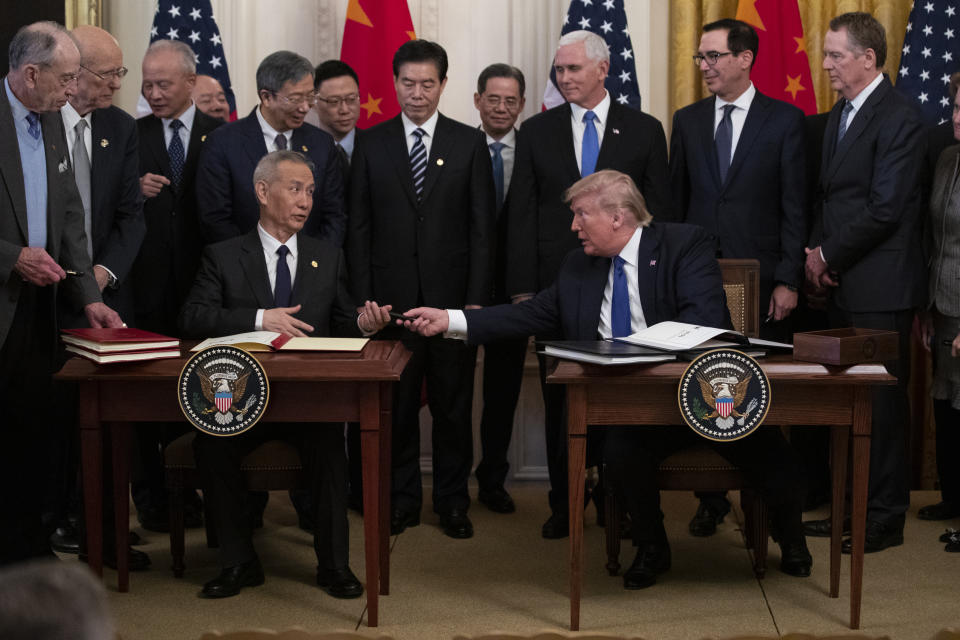 In this Jan. 15, 2020, photo, President Donald Trump hands a pen to Chinese Vice Premier Liu He after signing "phase one" of a US China trade agreement, in the East Room of the White House in Washington. (AP Photo/ Evan Vucci)