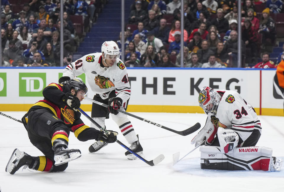 Chicago Blackhawks goalie Petr Mrazek (34) stops Vancouver Canucks' Pius Suter, left, as Blackhawks' Isaak Phillips (41) watches during the second period of an NHL hockey game in in Vancouver, British Columbia, Monday, Jan. 22, 2024. (Darryl Dyck/The Canadian Press via AP)