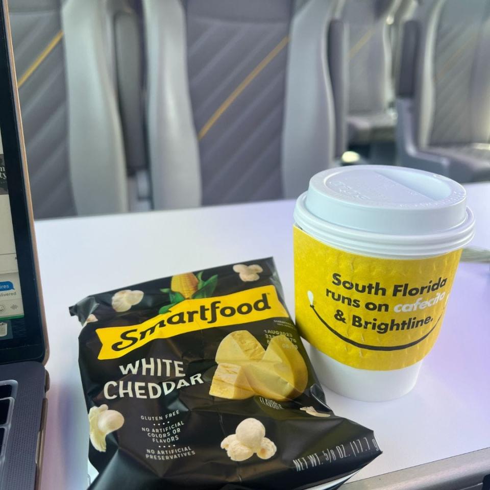 smartfood popcorn and coffee with yellow sleeve on train tray table