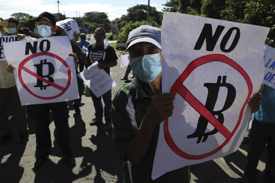 Farmers hold signs emblazoned with messages against the country adopting Bitcoin as legal tender, during a protest along the Pan-American Highway, in San Vicente, El Salvador, Tuesday, Sept. 7, 2021. El Salvador became the first country to adopt Bitcoin as legal tender Tuesday, but the rollout stumbled in its first hours and President Nayib Bukele informed that the digital wallet used for transactions was not functioning. (AP Photo/Salvador Melendez)