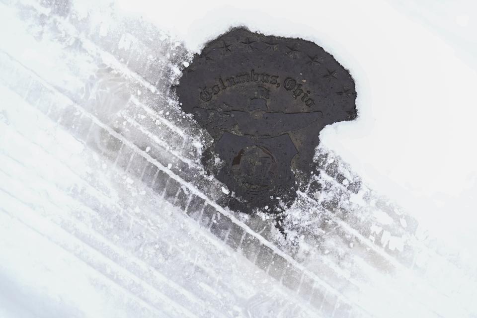 Fri., Feb. 4, 2022; Columbus, Ohio, USA; A manhole cover pokes out from underneath a snow-covered road as Winter Storm Landon passes through Greater Columbus.
