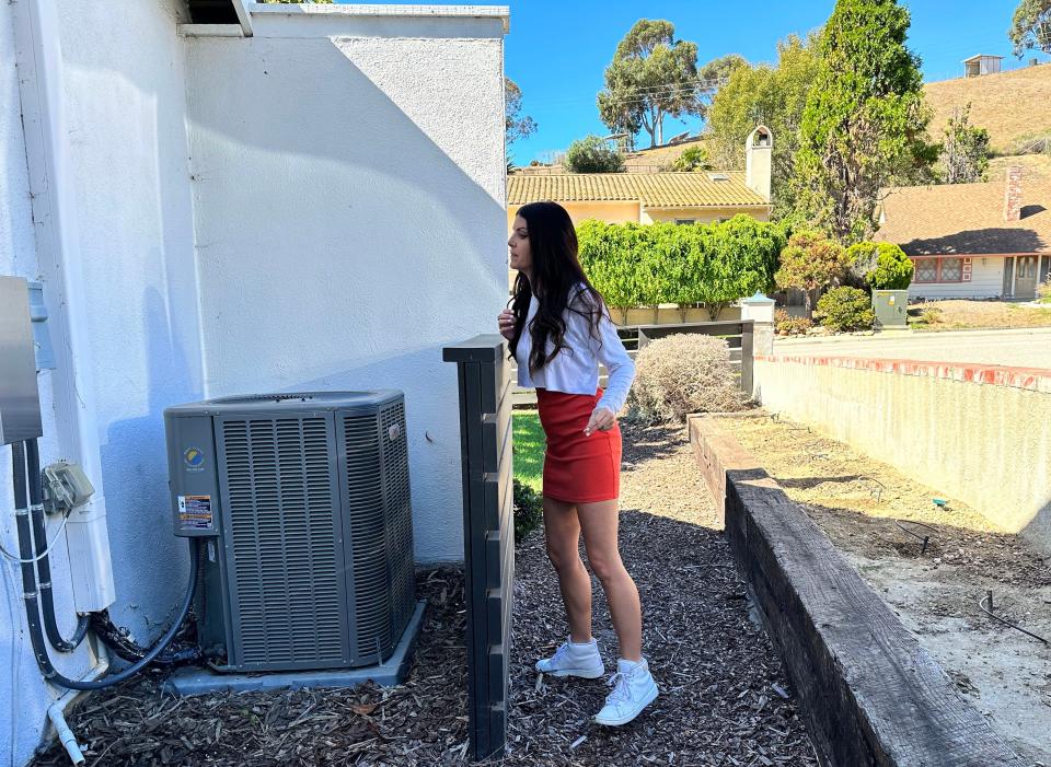 Micaela Dritz stands next to an air conditioning unit on the side of her house in Ventura on Oct. 5. Her family decided to install the system in 2017 when renovating and was the first of a wave of homeowners on the street to add air conditioning.