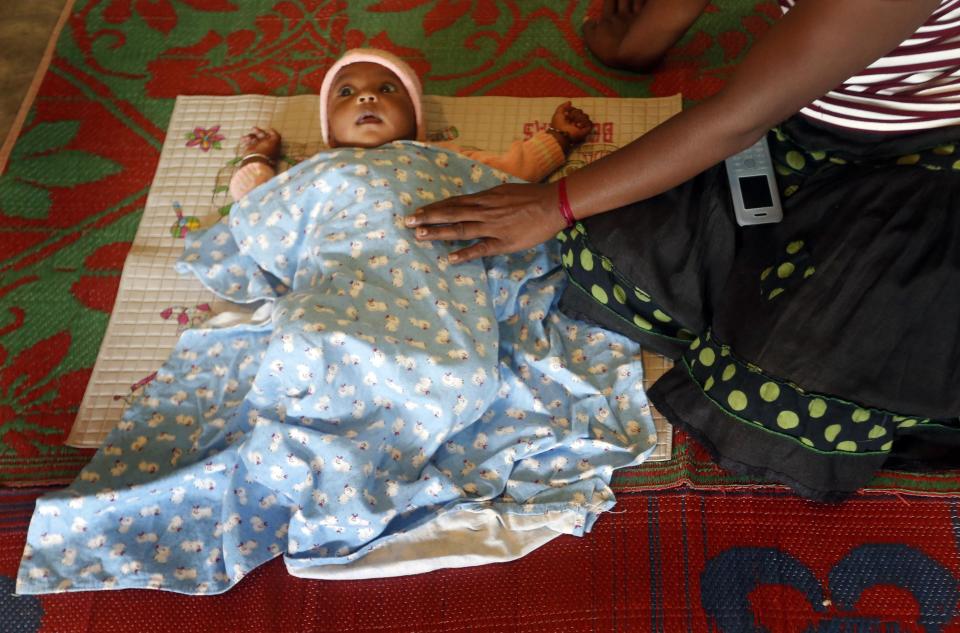 Woman sits next to her baby at a camp for people who have been displaced by a landslide at the Koslanda tea plantation near Haldummulla