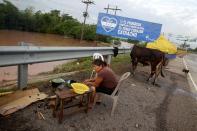 A woman cooks on the side of a highway after losing her home due to heavy rains caused by Hurricane Iota, in El Progreso