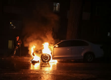 A man extinguishes a burning car of the embassy of Russia after a protest against the seizure by Russian special forces of three Ukrainian naval ships, which Russia blocked from passing through the Kerch Strait into the Sea of Azov in the Black Sea, in front of the Russian embassy in Kiev, Ukraine November 25, 2018. REUTERS/Serhii Nuzhnenko