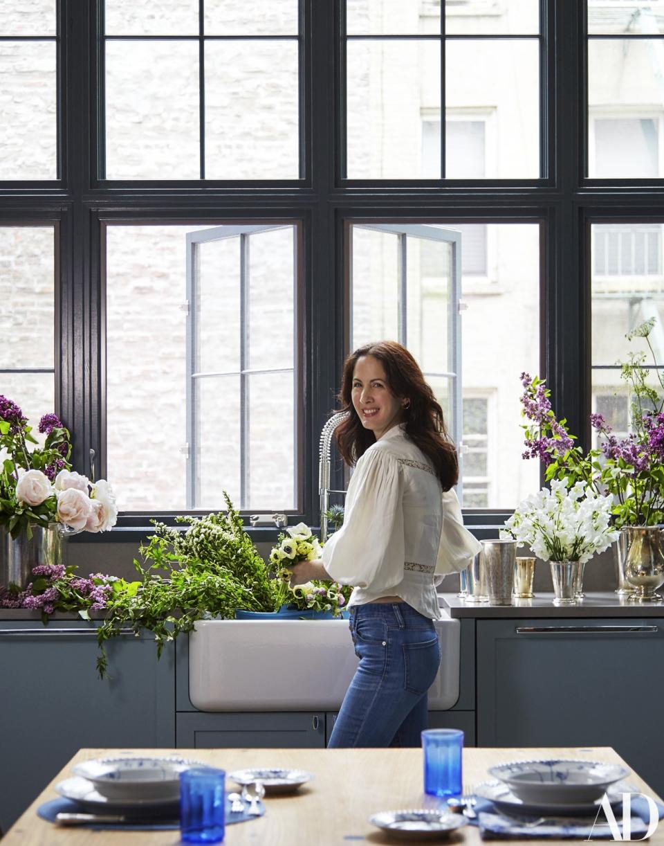 Herrera Lansing, in an Isabel Marant top, Madewell jeans, and Ana Khouri jewelry, arranges flowers at a Rohl sink in the kitchen. Fashion styling by Jessica Sailer van Lith.