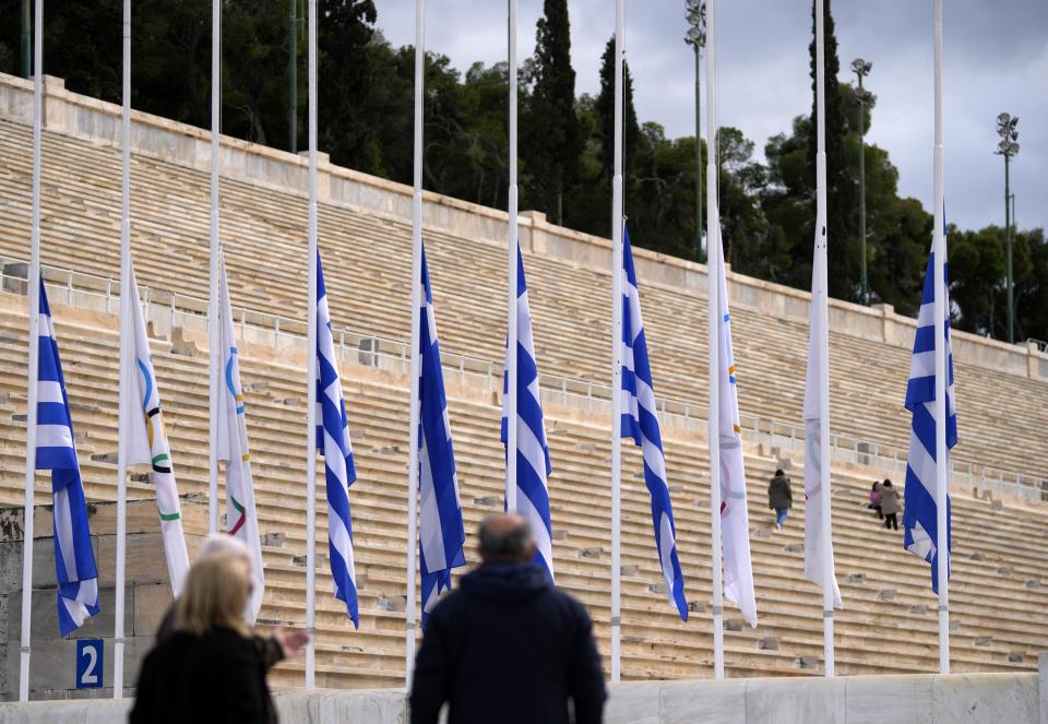 Greek and Olympic flags are seen at half-staff as the Hellenic Olympic Committee commemorate the former king of Greece who was an Olympic sailing gold medalist in Rome in 1960, at Panathinean stadium in Athens, Greece, Wednesday, Jan. 11, 2023. Greece's government says Constantine, the former and last king of Greece, will be buried as a private citizen in Tatoi, the former summer residence of Greece's royals where his parents and ancestors are buried. (AP Photo/Thanassis Stavrakis)