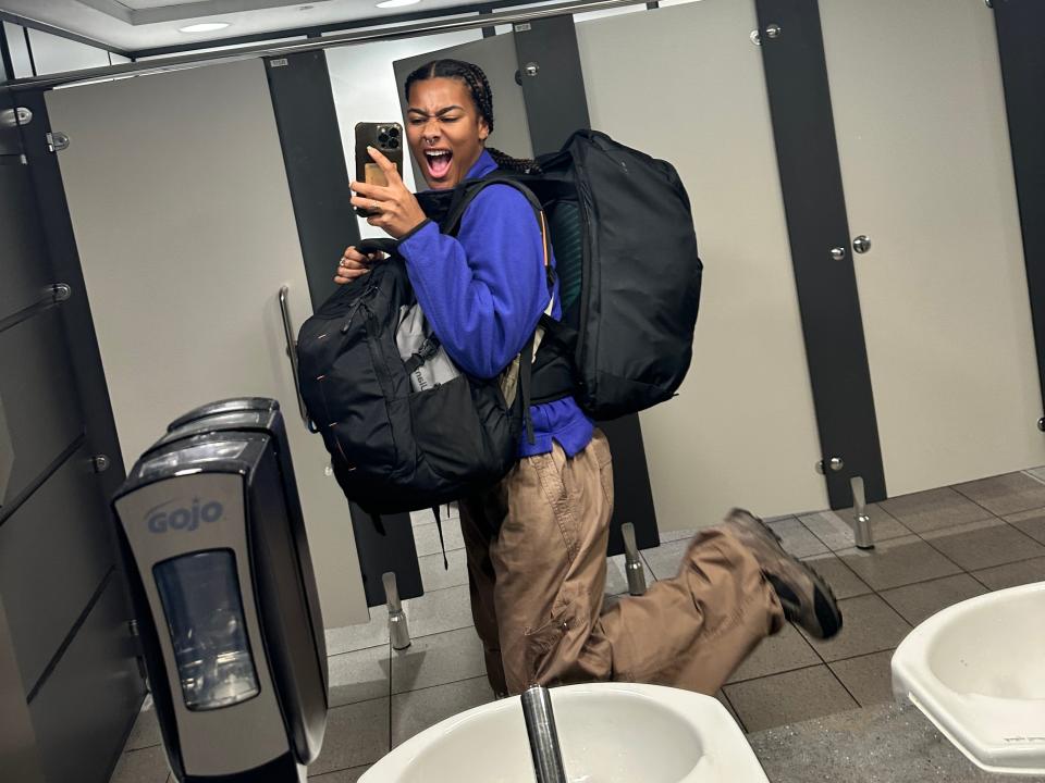 dominique taking a mirror while wearing two backpacks