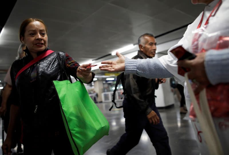 A woman receives a free condom from a member of an organization during an event organized by AIDS Healthcare Foundation for the International Condom Day, at a metro station in Mexico City