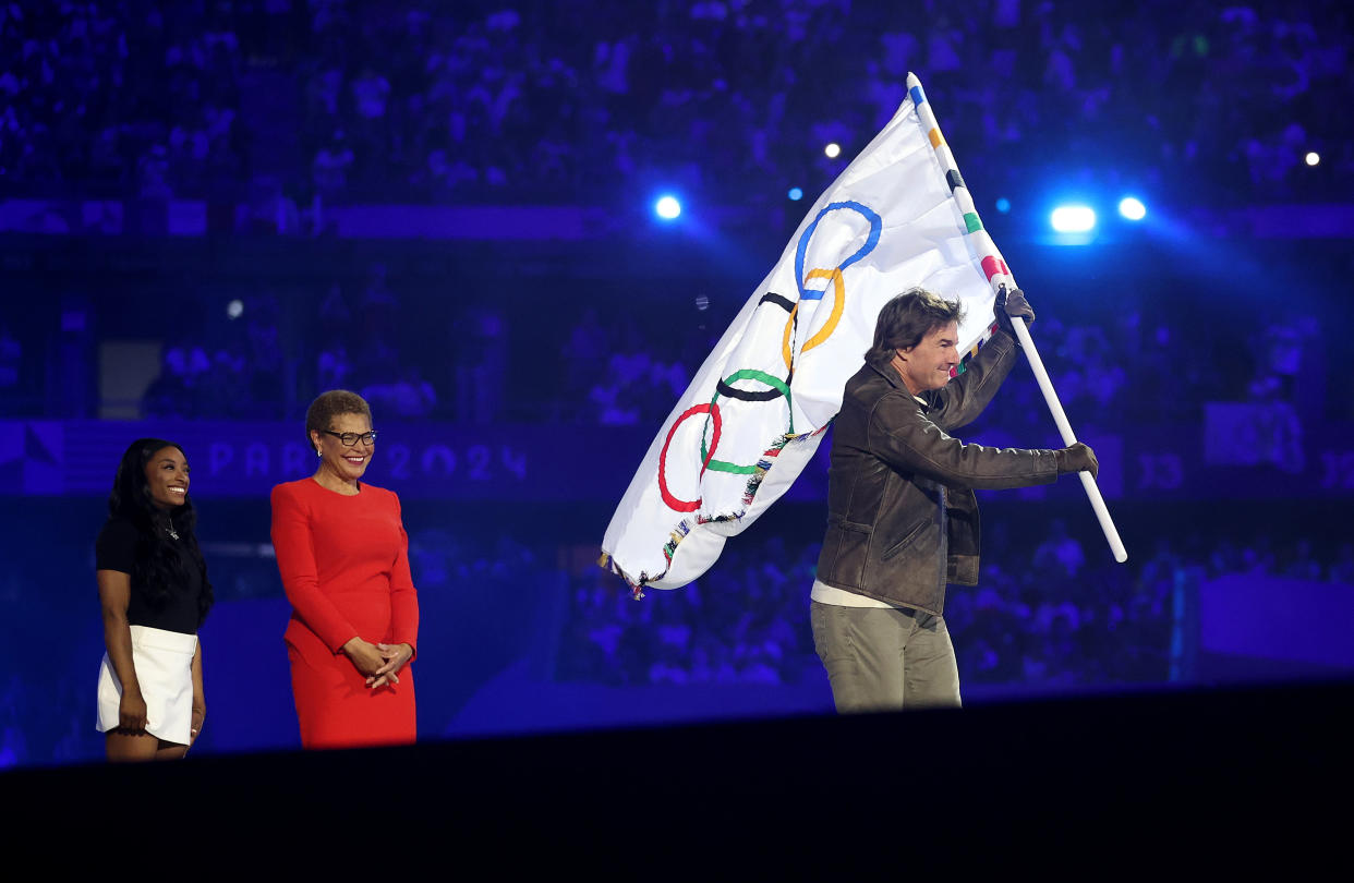 Tom Cruise carries the IOC Flag as Simone Biles of Team United States and Karen Bass, Mayor of Los Angeles, look on during the closing ceremony.