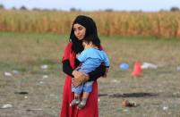 A migrant carries a baby after crossing the Hungarian-Serbian border near Roszke, Hungary August 26, 2015. REUTERS/Bernadett Szabo