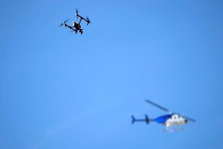 A news helicopter flies overhead as a firefighting drone hovers above a warehouse in Oakland, California, U.S. December 3, 2016. REUTERS/Stephen Lam