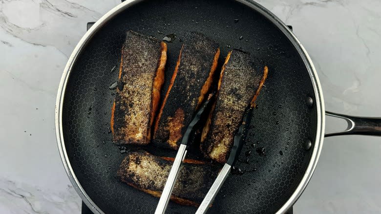 blackened salmon with tongs