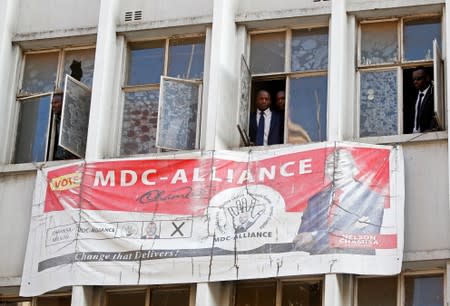 People peer through the windows of the headquarters of the opposition Movement for Democratic Change (MDC) party after police earlier banned planned protests in Harare