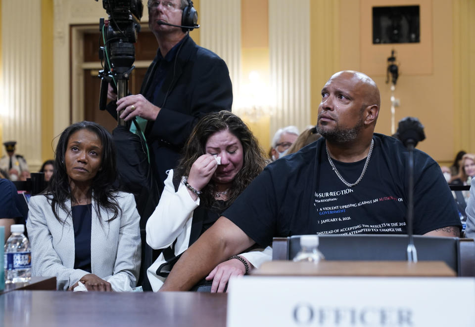 FILE - U.S. Capitol Police Sgt. Harry Dunn, right, consoles Sandra Garza, the long-time partner of fallen Capitol Police Officer Brian Sicknick, center, as a video of the Jan. 6 attack on the U.S. Capitol is played during a public hearing of the House select committee investigating the attack is held on Capitol Hill, June 9, 2022, in Washington. Serena Liebengood, widow of Capitol Police officer Howie Liebengood, reacts at left. (AP Photo/Andrew Harnik, File)