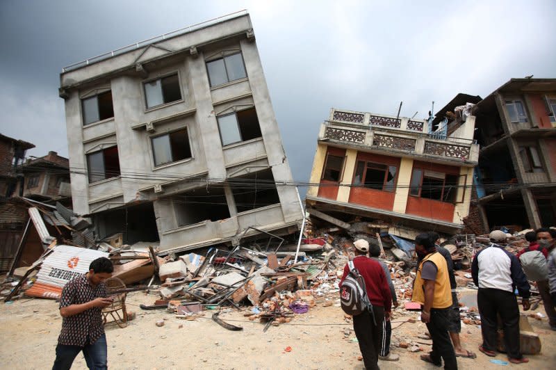 Nepalesep walk in front of collapsed buildings in Kathmandu, which was damaged in the earthquake April 25, 2015. File Photo by Sanjog Manandhar/UPI