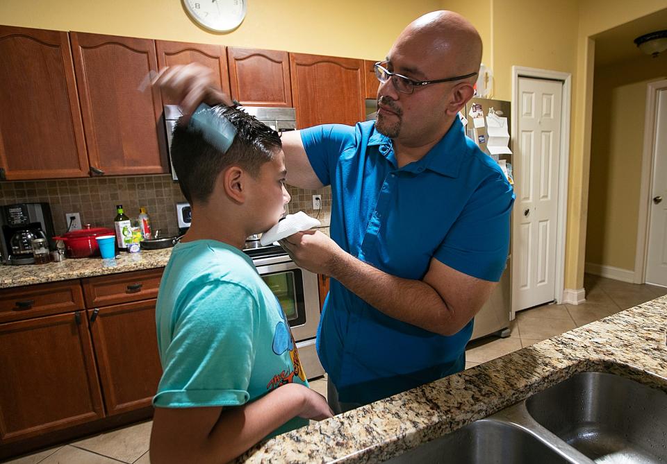 Cape Coral resident Dereck Marquez combs his son Daniel's hair Friday, June 24, 2022, at their home. Daniel was arrested by the Lee County Sheriff's Office after allegedly making a threat.