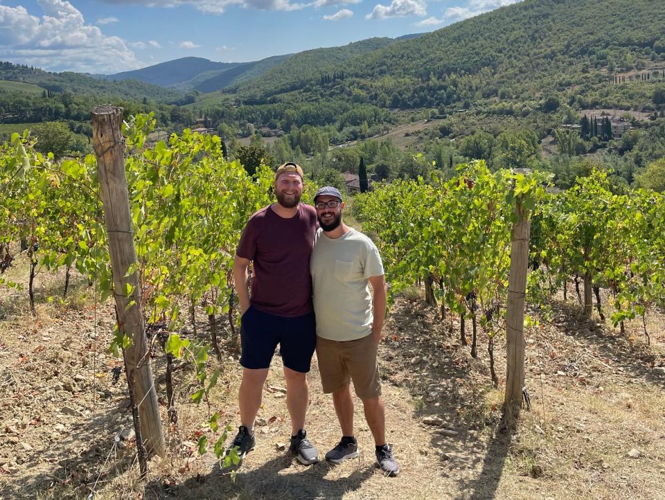 The author and his husband standing in a vineyard in Italy