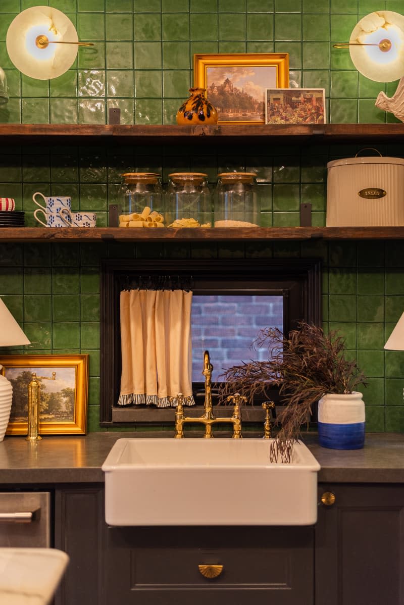 Kitchen with black cabinets and green tiled backsplash.