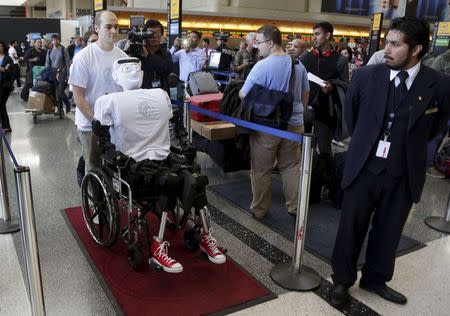 Alexander Herzog, a doctoral student at Max Planck Society, pushes 'Athena', the first 'humanoid' robot to fly as a passenger, as they arrive at Los Angeles International Airport, California December 15, 2014. REUTERS/Jonathan Alcorn