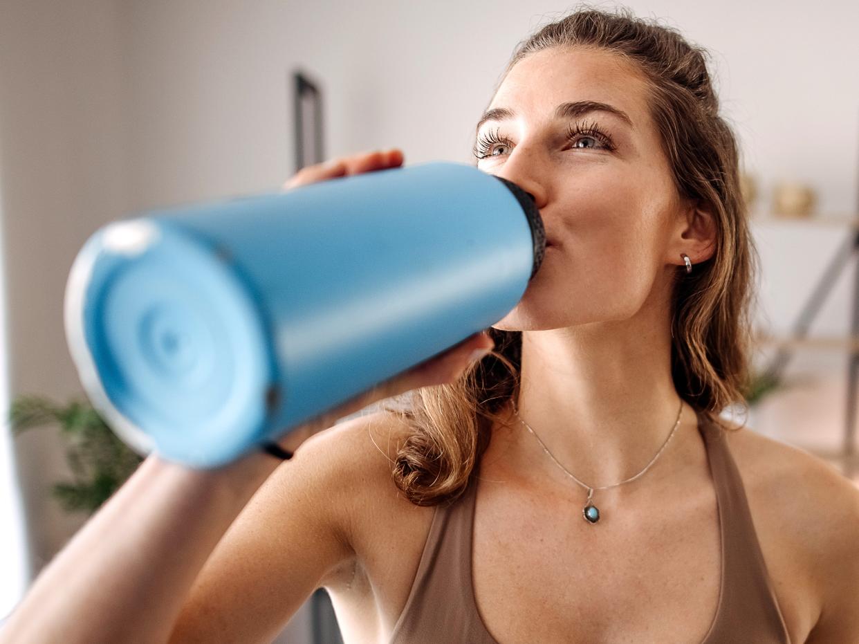 Woman drinking water from a big blue water bottle