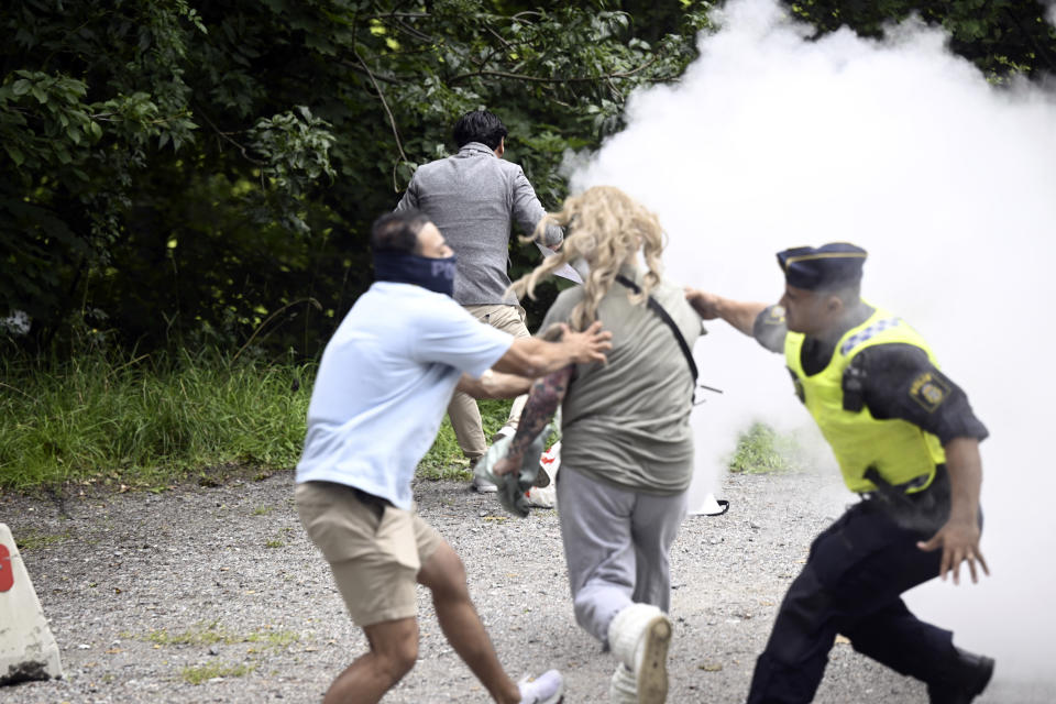 A counter-demonstrator extinguishes a Quran on fire outside the Iranian embassy, in Stockholm, Friday, Aug. 18, 2023. A woman with a fire extinguisher on Friday raced toward the man who set fire to a Quran outside the Iranian Embassy in Stockholm but was stopped by plain clothes officers. Swedish media said the woman, who was not identified, was detained, suspected of disturbing public order and violence against a police officer. Salwan Momika, the protester, was not injured. (Fredrik Sandberg/TT News Agency via AP)