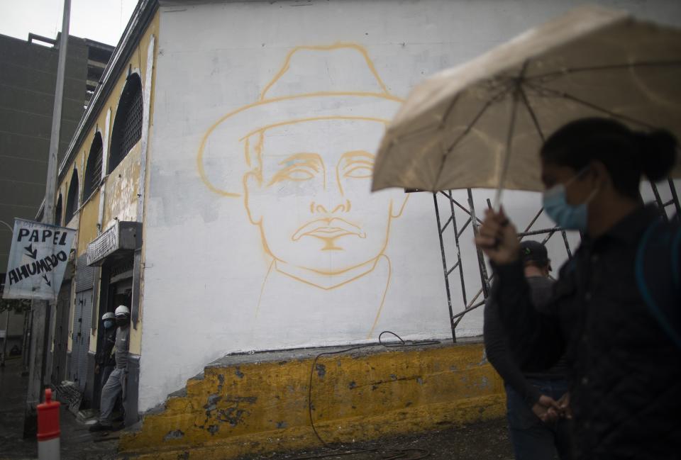 A woman pass close to unfinished mural of Venezuelan popular saint, Dr. Jose Gregorio Hernandez, in Caracas, Venezuela, Wednesday, April 28, 2021. Known as the doctor of the poor, Hernandez is set to be beatified by the Catholic church, a step towards sainthood, on April 30th. (AP Photo/Ariana Cubillos)