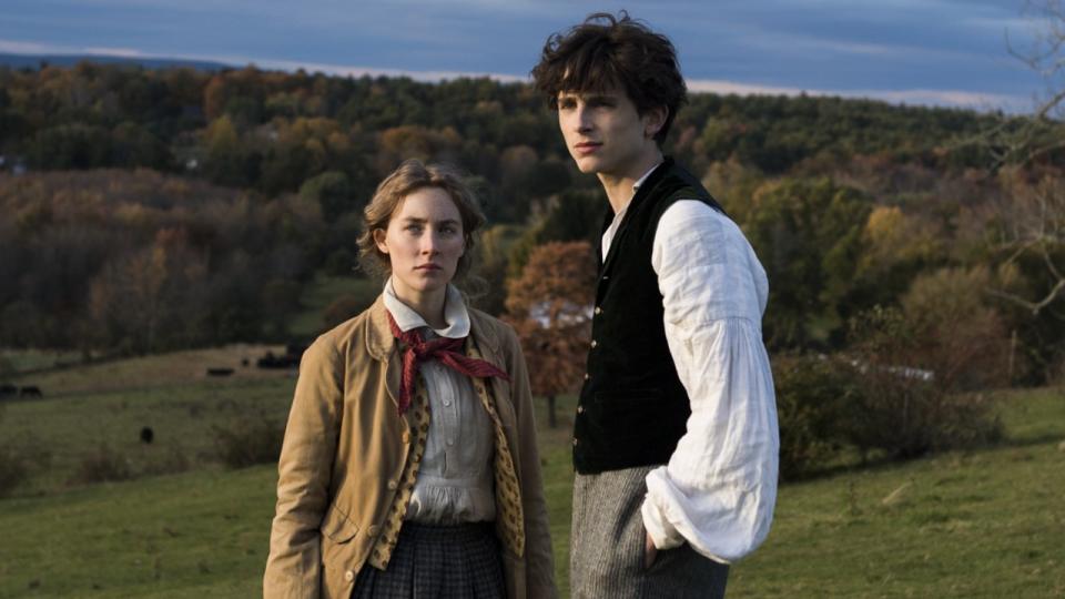 Saoirse Ronan as Jo standing slightly behind Timothee Chalamet as Laurie in Little Women.