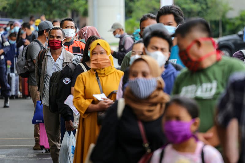 FILE PHOTO: Passengers wearing protective face masks line up to rapid antigen test