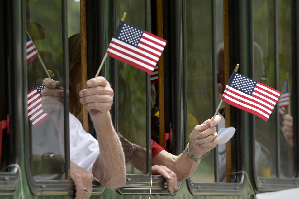 <p>People wave American flags from the Aiken County Historical Museum trolley bus as it makes its way down the parade route during the Aiken Memorial Day parade Saturday, May 28, 2016, in Aiken, S.C.. (Michael Holahan/The Augusta Chronicle via AP) </p>