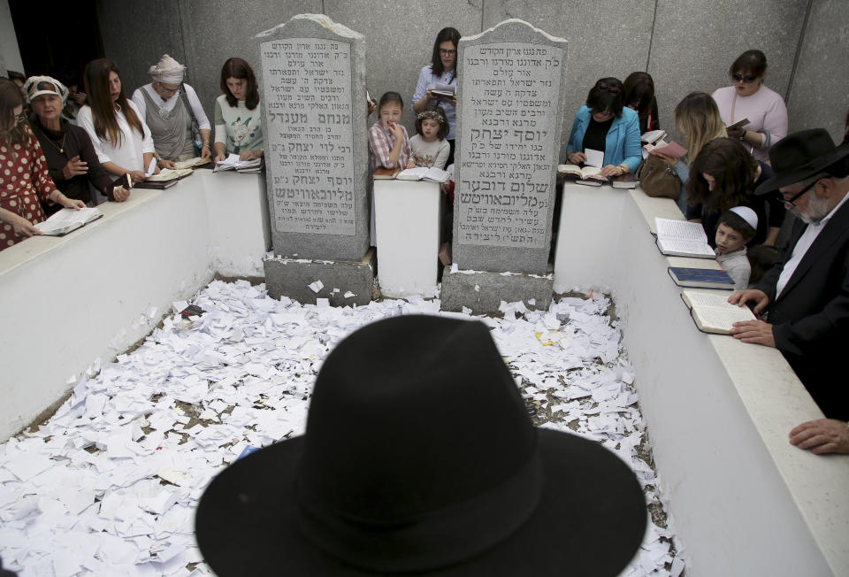 In this July 2, 2019 photo, people pray at the gravesite of Rabbi Menachem M. Schneerson in the Queens borough of New York. Men and women, young and old, make their way from around the city, the country and the world to this unassuming site, the burial place of Rabbi Menachem Mendel Schneerson, to pay their respects to the life and teachings of the revered Jewish leader of the Chabad-Lubavitch movement who died twenty-five years ago in June 1994. (AP Photo/Seth Wenig)