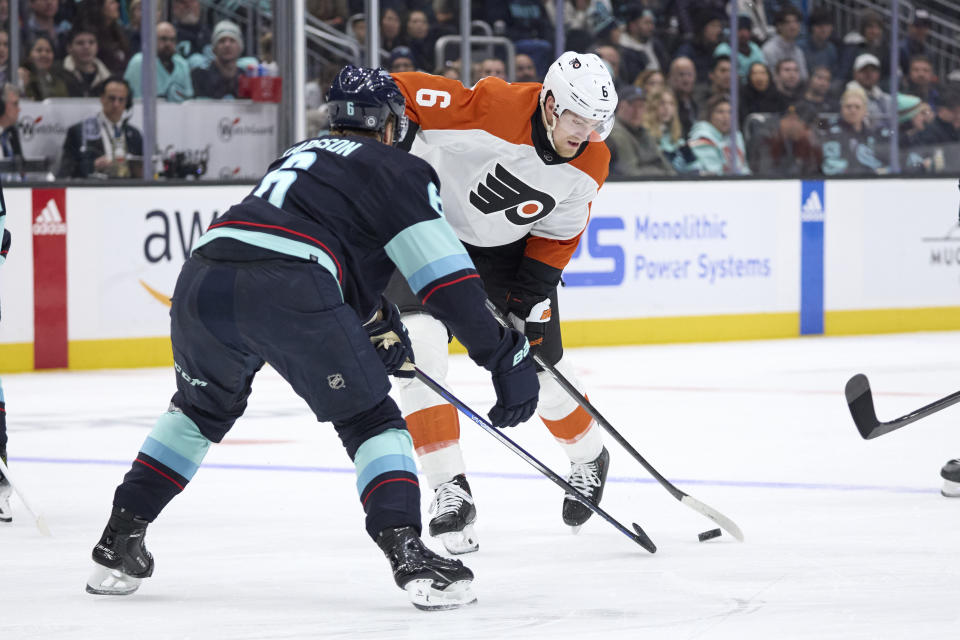 Philadelphia Flyers defenseman Travis Sanheim, right, works to control the puck with Seattle Kraken defenseman Adam Larsson, left, defending during the second period of an NHL hockey game, Friday, Dec. 29, 2023, in Seattle. (AP Photo/John Froschauer)