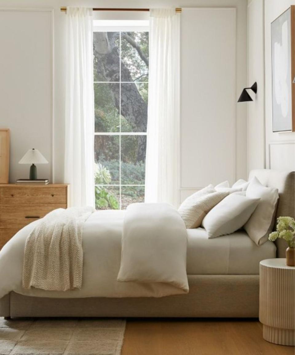 A neutral bedroom with a bed and a set of drawers