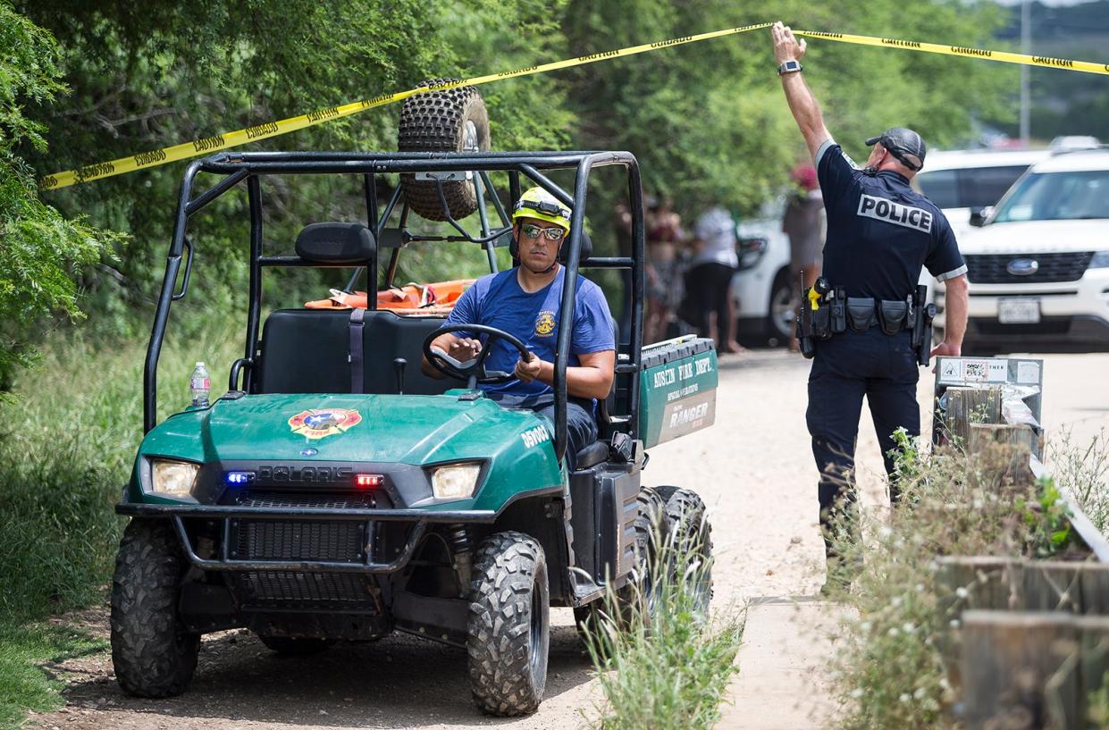 An Austin police officer lifts crime scene tape for a special operations vehicle to pass under at a trailhead to the Barton Creek greenbelt in 2018. An app, What3Words, can help more easily find people who need help in wooded areas or other locales.