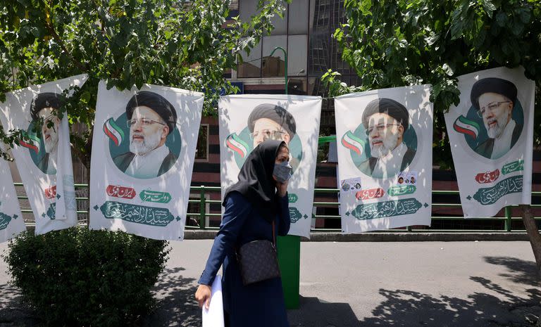 Una mujer en Teherán camina frente a los posters del candidato conservador Ebrahim Raisi