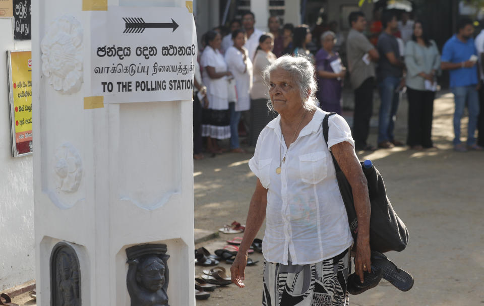 A Sri Lankan elderly woman leaves after casting her vote as others queue at a polling station during the presidential election in Colombo, Sri Lanka, Saturday, Nov. 16, 2019. Polls opened in Sri Lanka’s presidential election Saturday after weeks of campaigning that largely focused on national security and religious extremism in the backdrop of the deadly Islamic State-inspired suicide bomb attacks on Easter Sunday. (AP Photo/Eranga Jayawardena)