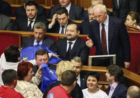 Opposition deputies try to pass a European Union flag to Ukraine's First Deputy Prime Minister Serhiy Arbuzov (C) and Energy Minister Yuri Boiko (L) as Prime Minister Mykola Azarov (R) gestures during a session of parliament in Kiev November 22, 2013. REUTERS/Gleb Garanich