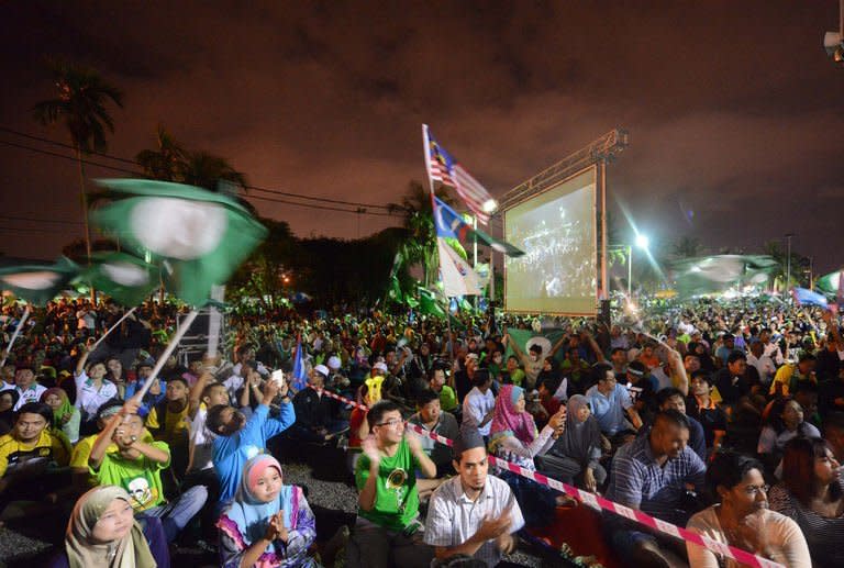 Opposition supporters cheer and wave party flags as they wait for the possible arrival of opposition leader Anwar Ibrahim in Seberang Jaya, Penang on May 4, 2013