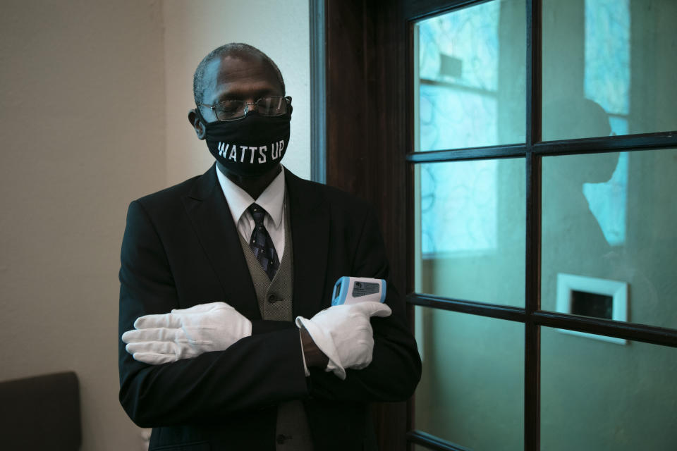 Holding an infrared thermometer, usher Frank Scott prays during a Sunday service at Tree of Life Missionary Baptist Church on Sunday, June 21, 2020, in the Watts neighborhood of Los Angeles. (AP Photo/Jae C. Hong)