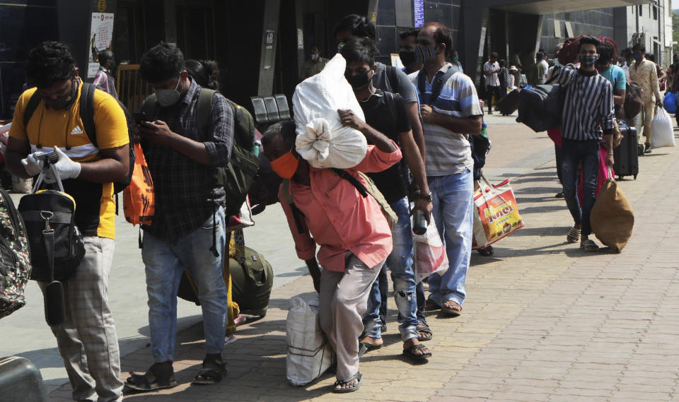 People wearing masks as a precaution against the coronavirus walk to board trains at Lokmanya Tilak Terminus in Mumbai, India, Friday, April 16, 2021. Migrant workers are swarming rail stations in India's financial capital Mumbai to go to their home villages as virus-control measures dry up work in the hard-hit region. The government of Maharashtra state imposed lockdown-like curbs on Wednesday for 15 days to check the spread of the virus. It closed most industries, businesses and public places and limited the movement of people, but didn’t stop the bus, train and air services. An exodus ensued, with panicked day laborers hauling backpacks onto overcrowded trains leaving Mumbai, travel that raises fears of infections spreading in rural areas. (AP Photo/Rajanish Kakade)