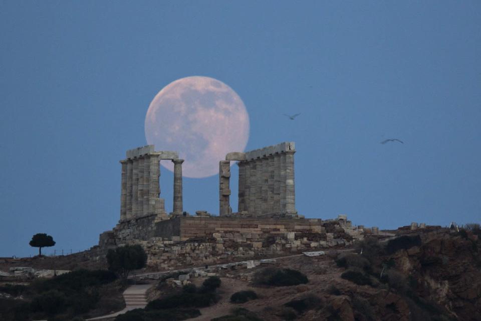 Seagulls fly as the full moon rises behind the ancient marble Temple of Poseidon at Cape Sounion, southeast of Athens, on the eve of the summer solstice on June 20, 2016. (AP Photo/Petros Giannakouris)